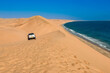 Safari trip by car through sand dunes on ocean shore of Sandwich harbour, extreme travel adventure on Atlantic coast of Namibia, South Africa
