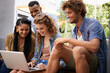 © Mariusz/peopleimages.com - Laptop, education and group of friends on college or school campus together for learning or study. Computer, smile or university project with happy young man and woman students on academy stairs