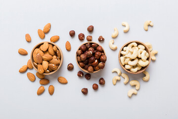 Wall Mural - Assortment of nuts in wooden bowl on colored table. Cashew, hazelnuts, walnuts, almonds. Mix of nuts Top view with copy space