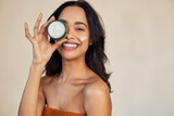 Fototapeta  - Hispanic woman holding beauty cream jar while smiling
