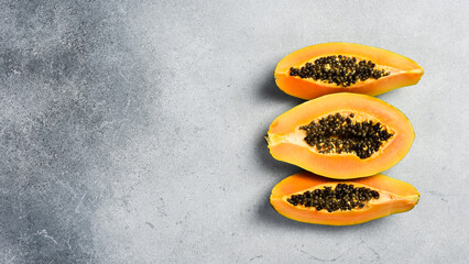 Wall Mural - Close up of exotic papaya fruit. Sliced papaya on a gray concrete background.