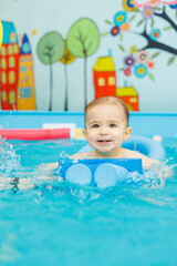 Wall Mural - A little boy is swimming in the pool. Teaching children to swim. Children's swimming school