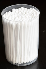 Macro view of white cotton ear cleaning buds arranged in black background nicely in a container