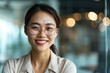 © Generative ART - smiling Asian entrepreneur female with glasses looking at camera in office setting