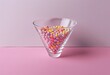 Bright holiday: multi-colored sprinkles in a glass bowl on a pink background - a high-quality image for decorating a party and sweets