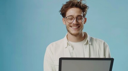 Poster - Millennial in glasses working online or communicating on laptop computer in blue studio background