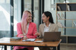 © Parichat - Two businesswomen working together at a boardroom during a meeting in a modern office.
