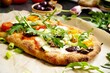 Homemade vegetarian Pinsa with tomato, olive, arugula and mozzarella