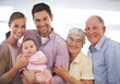 © Mapodile/peopleimages.com - Portrait, happy big family and baby in home for bonding, love and infant together with parents. Face, grandparents and child with mother, father and kid in living room with a smile for connection