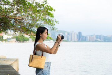 Sticker - Woman use digital camera to take photo beside the sea