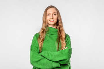 Wall Mural - Portrait of young woman looking at camera with confident facial expression, wear trendy knitwear green sweater, standing over neutral background