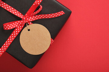 Wall Mural - Black craft gift box with blank circle tag on red background. Place for your text