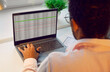 © Studio Romantic - Businessman or financial accountant working with business spreadsheets on laptop computer. African American man sitting at office desk and looking at screen of notebook PC, back view, over shoulder
