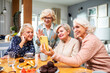 © Marko Geber - Group of senior women using smartphone together at home