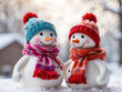 Two cute toy snowmen in hats and scarves.