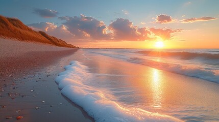  the sun is setting over a beach with waves coming in to shore and sand blowing in the foreground, and a cliff on the far side of the beach.