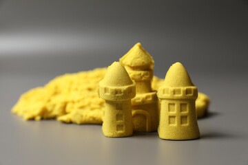 Poster - Castle figures made of yellow kinetic sand on grey background, closeup. Space for text