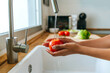 Close-up of woman hands washing tomato in the kitchen.