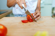 Close-up of woman hands cutting tomato.