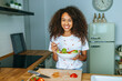 Woman with lettuce and tomato salad in the kitchen.