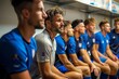 © Pinklife - A team of blue-clad athletes, their faces beaming with camaraderie and sporting gear in hand, sit together in the intimate setting of an indoor locker room