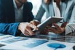© Ifti Digital - A diverse group of individuals gathered around a table, engaged in a discussion as they interact with a tablet, Focused business professionals working together on a digital tablet, AI Generated