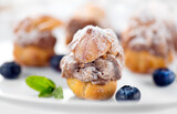 Fototapeta  - Profiterole or cream puff with filling,  powdered sugar topping with berries, on white background. Fresh homemade Cream Puffs, cake, tasty French choux puff, ecler, dessert closeup. Pastries on plate