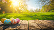 Colorful Easter eggs on a wooden table in the foreground and sunlit green grass in the background