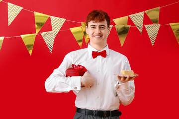 Sticker - Young man with piece of birthday cake and gift on red background