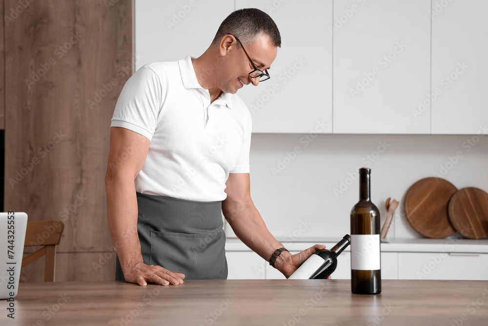 Mature man with bottle of wine in kitchen