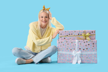 Poster - Happy mature woman with gift boxes on blue background