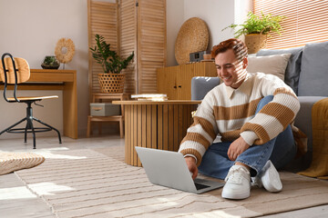 Sticker - Redhead young happy man with laptop sitting on floor at home