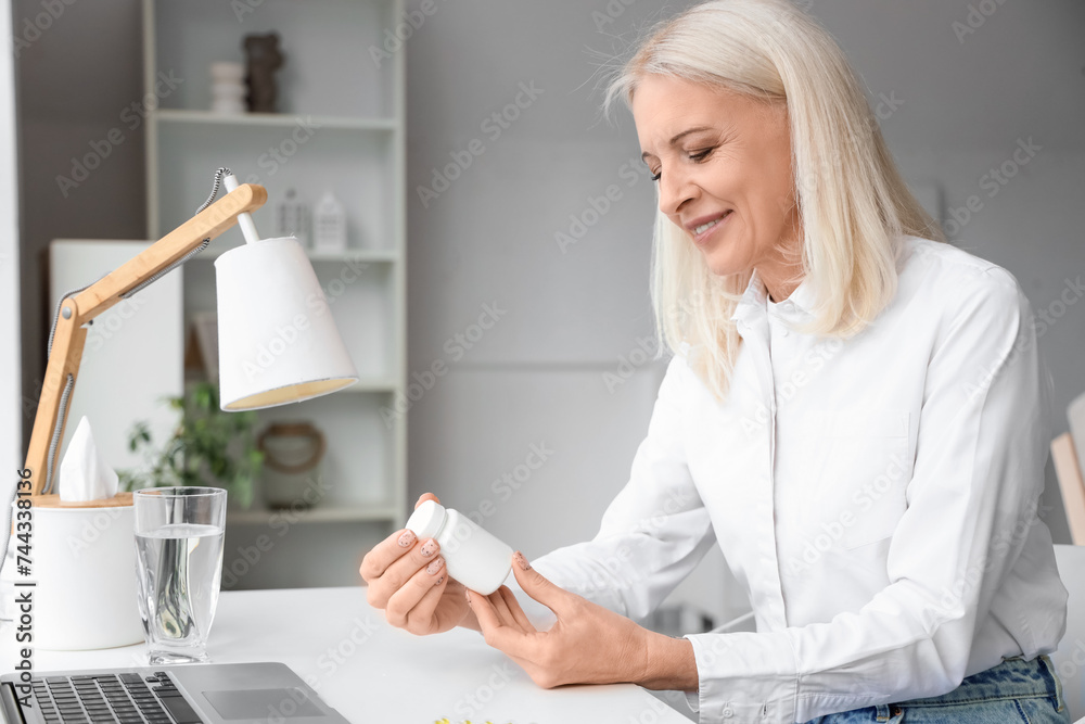 Mature woman holding bottle with pills at home
