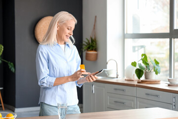 Wall Mural - Mature woman checking pills description online in kitchen