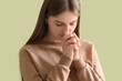 Young woman praying on green background, closeup