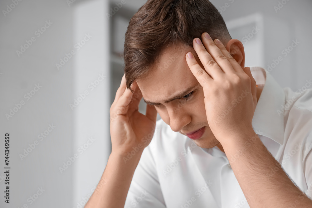 Young man suffering from headache at home, closeup