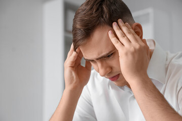 Canvas Print - Young man suffering from headache at home, closeup