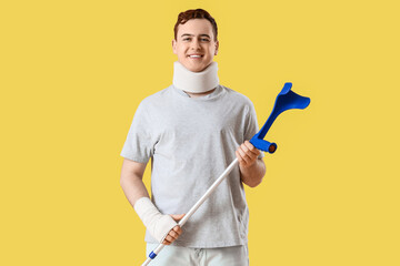 Sticker - Injured young man after accident with crutch on yellow background