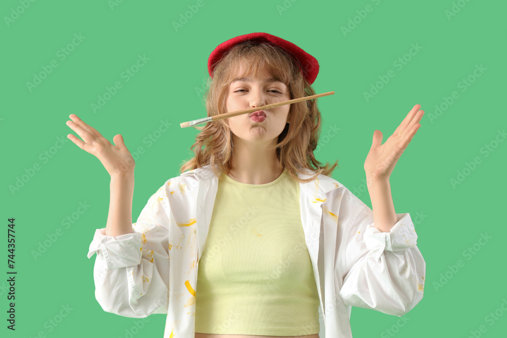 Funny female artist with paint brush on green background