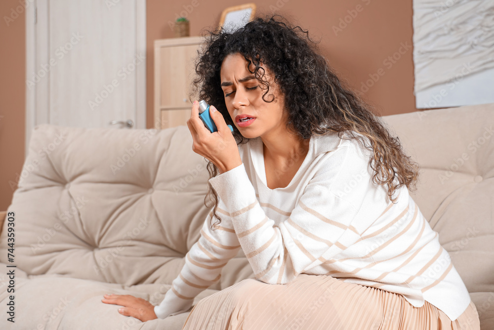 Young African-American woman using asthma inhaler at home