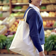 Man holding reusable white blank tote bag shopping in market or groceries store