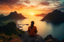 Aerial view of a woman watching the sunset on the picturesque mountain beach
