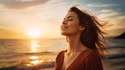 Wall Mural - A happy beautiful young smiling woman with long hair flying in the wind, stands on the seashore with her eyes closed at sunset. Golden Hour, Pleasure, Joy, Travel, Summer, Vacation concepts.