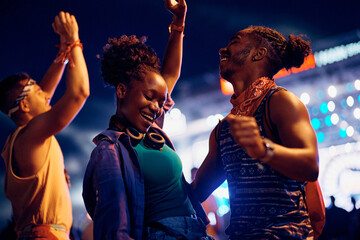 Wall Mural - Black carefree couple dancing and having fun on summer music festival at night.