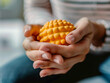 © Gia - person's hands tightly gripping a stress ball, focus on the tension in the fingers, the ball's texture, set against a blurred background of an anxiety-relief clinic