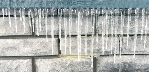 Wall Mural - Icicles hang from the brick wall of the building