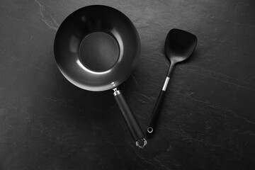 Sticker - Black metal wok and spatula on dark textured table, top view