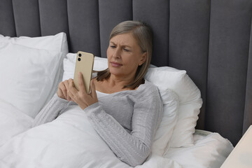 Poster - Menopause. Sleepless woman using smartphone in bed indoors