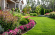 © somruethai - Perfect manicured lawn and flowerbed with shrubs in sunshine, on a backdrop of residential house backyard