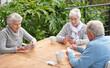 © peopleimages.com - Elderly people, card games and coffee at table with outdoor background for retirement and old age. Group, seniors or family with beverages and thinking for poker, relax and break together on patio